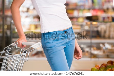 Unrecognizable female customer shopping at supermarket with trolley