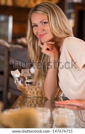 Young caucasian woman in front of bakery food store window, smiling and looking at camera