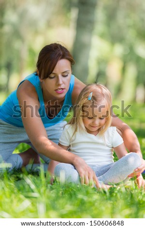 Mother and daughter doing exercise outdoors - mother teaching her daughter how to do exercises