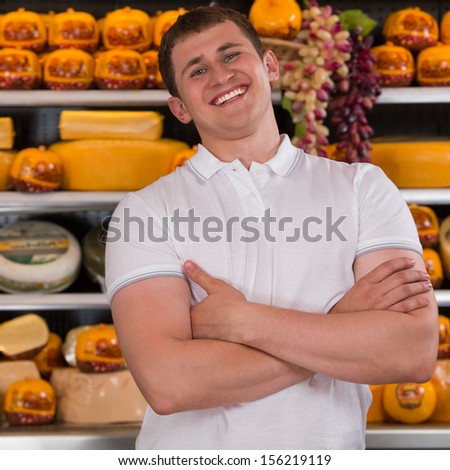 Handsome male owner of a cheese store standing with folded arms looking at the camera with a confident smile