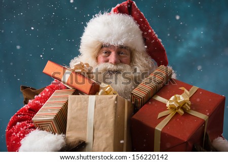 Photo Of Happy Santa Claus Outdoors In Snowfall Carrying Gifts To Children