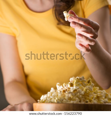Unrecognizable woman eating popcorn at the cinema