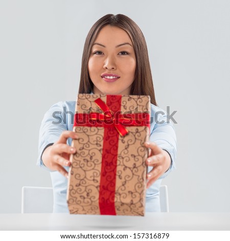 Portrait of young business woman sitting at her desk with a gift box