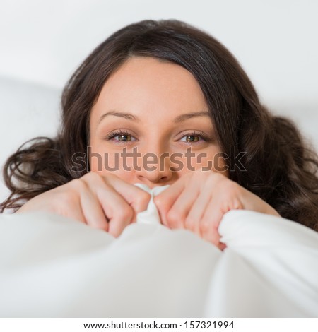 Beautiful young girl hides her face in bed and flirting