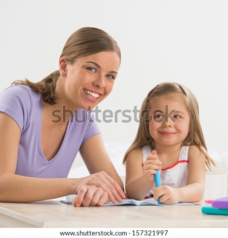 Mother and daughter at home. Mom teaches little girl to draw and write