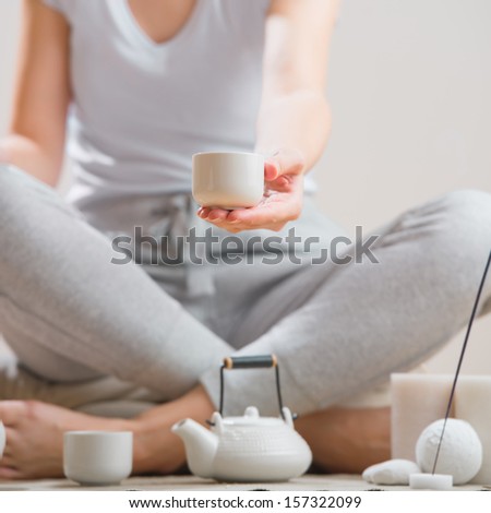 Woman sitting on floor of her home and holding tea cup. Aromatherapy, meditation and healthy life concept