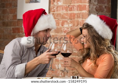 Couple toasting wine glasses at restaurant while celebrating Christmas