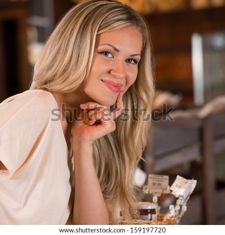 Young caucasian woman in front of bakery food store window, smiling and looking at camera