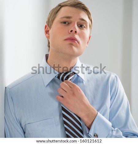 Portrait of a successful young business man adjusting neck tie