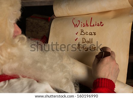Santa Claus sitting at home and writing on old paper roll to do list with feather pen and ink at night with candle light. Authentic vintage style portrait.