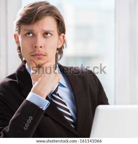 Portrait of serious thinking business man with laptop