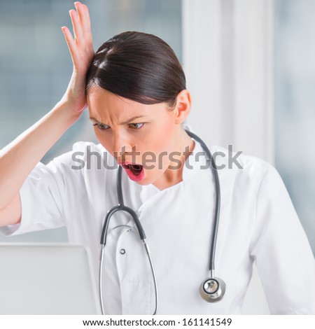 Portrait of a female doctor using her laptop computer at clinic and confused by something