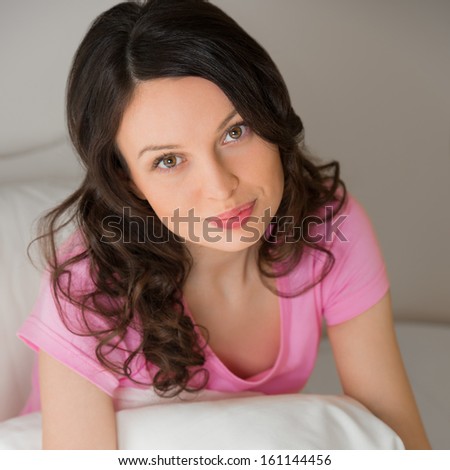 beautiful young brunette woman on the bed at home looking at camera