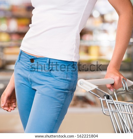 Unrecognizable female customer shopping at supermarket with trolley
