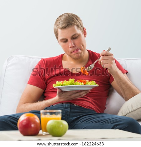 Young man eating vegetarian salad with appetite