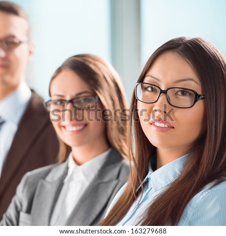 Group of a successful business people standing together at office and smiling