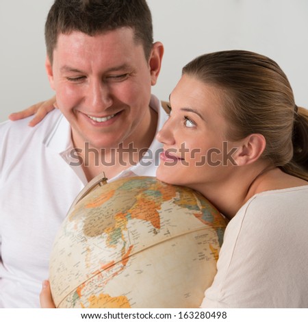 Portrait of happy romantic couple sitting together at home with globe planning their vacation and trip. Traveling concept