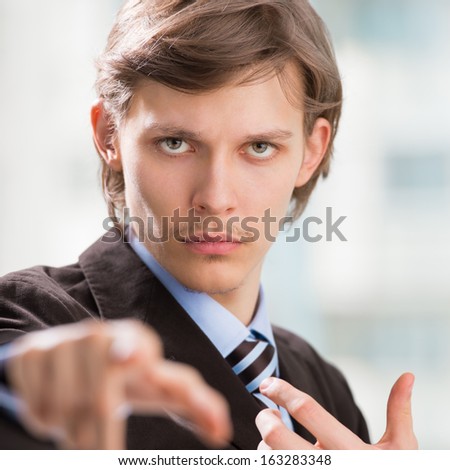 Portrait of adult business man pointing at you at his office