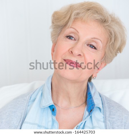 Portrait of an attractive elegant senior woman relaxing and dreaming at home