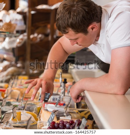 Shopkeeper working in a cheese glass case in a grocery store