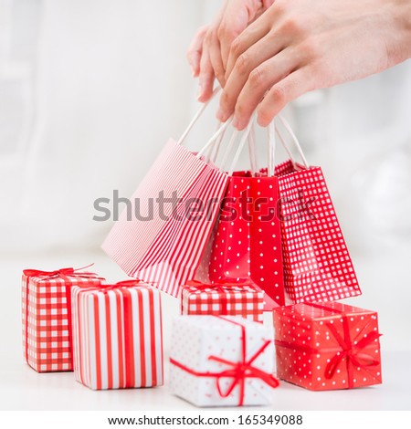 Female hands holding red gift bags near Gift boxes - shopping and holiday concept