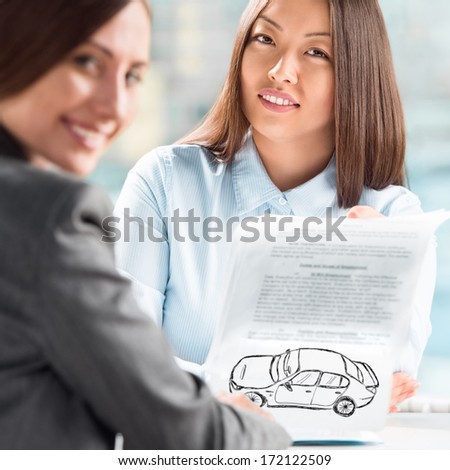 Two business women talking and signing credit or insurance contract at office