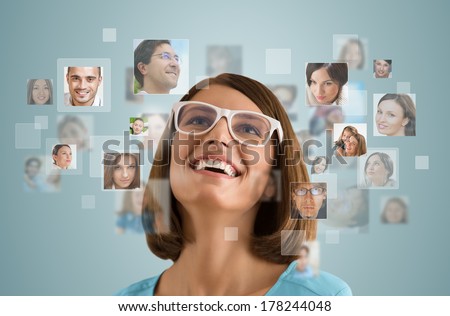 Young woman standing and smiling with many different people\'s faces around her. Technology social media network of friends and communication.