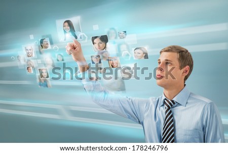 Portrait of young businessman choosing people for his business team using virtual computer interface