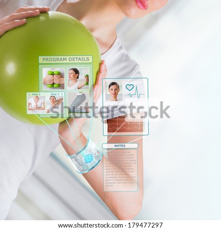 Woman doing exercise with ball wearing smart wearable device with futuristic interface