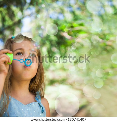 Five years old caucasian child girl blowing soap bubbles outdoor at summer park - happy carefree childhood
