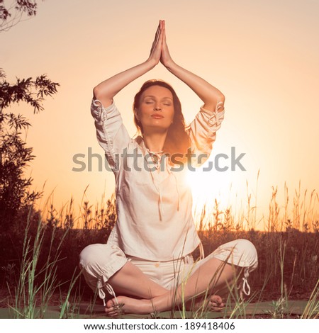 Yoga woman during sunset meditating against the sun outdoors. Retro filter photo