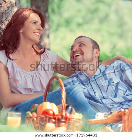 Adult couple picnicking in the park under the tree. Retro style photo