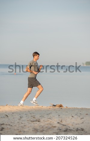Man athlete/runner running on beach - jog workout well-being concept