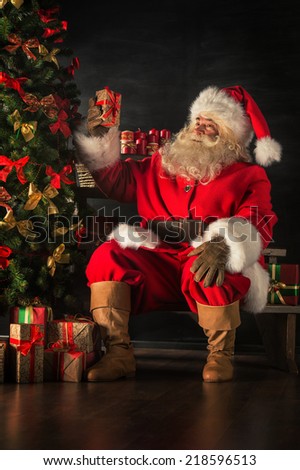 Santa Claus brought gifts for Christmas. Santa is placing gift boxes under Christmas tree