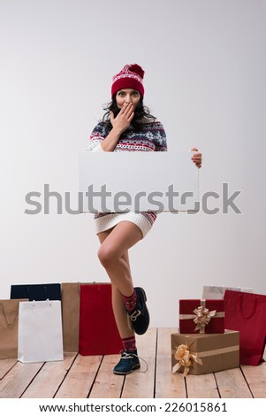 Christmas woman hold big white card copyspace. Winter knitted beanie hat. Full length.