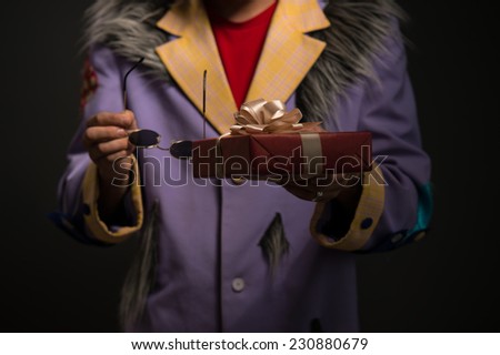 Unrecognizable Clown man with Christmas gift box on black background