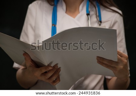Unrecognizable female doctor reading medical record