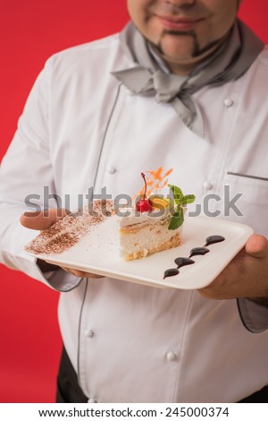 Portrait of caucasian man with chef uniform sharing fresh cake. Professional serving