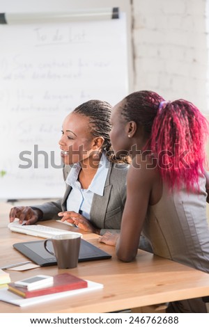 Image of two young african businesswomen using computer at meeting