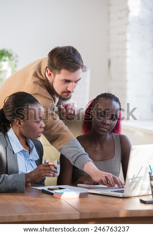 Image of group of three young business people using laptop at meeting