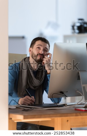 Artist or designer thinking while drawing something on graphic tablet at the office