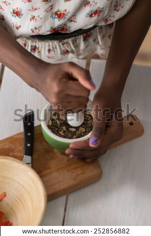 Unrecognizable african woman crushing spices while cooking at home