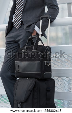 Unrecognizable businessman in urban environment of airport with suitcase