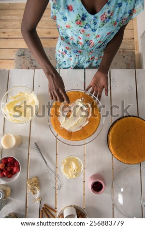 Beautiful young african woman cooking cake at kitchen. Top view