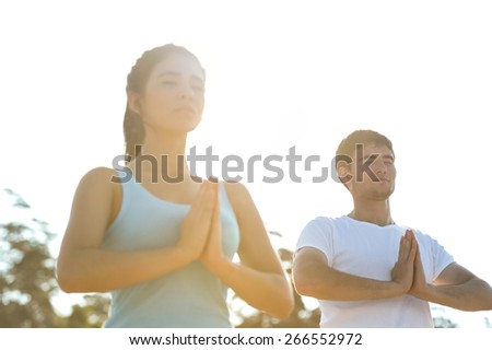 Fitness, sport, friendship and lifestyle concept - smiling couple making meditation yoga exercises on beach at morning
