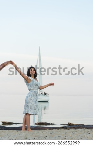 Free woman enjoying freedom feeling happy at beach at morning. Beautiful serene woman and welcoming yacht and sailor with arms opened outstretched up. Hispanic Caucasian female model