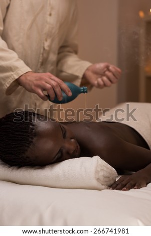 Beautiful young african woman enjoys body back massage in a luxury spa resort
