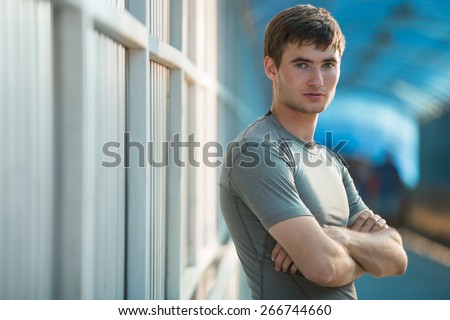 Jogger resting after running. Man runner taking a break during training outdoors in city. Young Caucasian male fitness model after work out.
