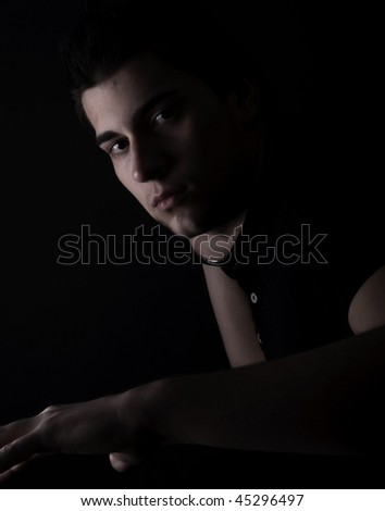 Portrait of a cool guy: posing on dark background with side light