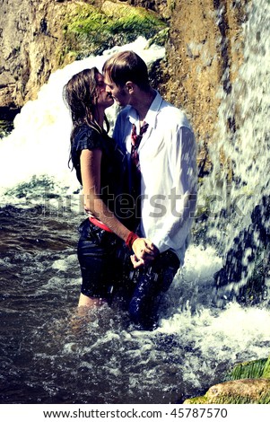 Portrait of a young sexy couple drinking a tea and making love on waterfall